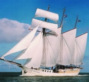 ein Dreimaster-Segelschiff mit geblähten Segeln auf offener See