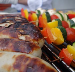 Grossaufnahme links knusprig gegrilte Würstel und rechts Gemüsespieße