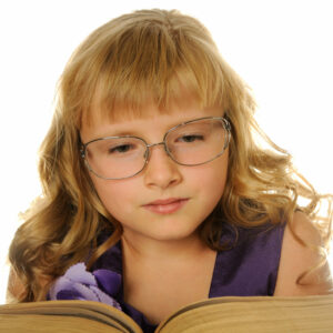 ein circa 8jähriges Mädchen mit blonden langen Haaren, einem Pony, mit Brille, liest mit ernstem Gesicht in einem dicken Buch, kein Hintergrund